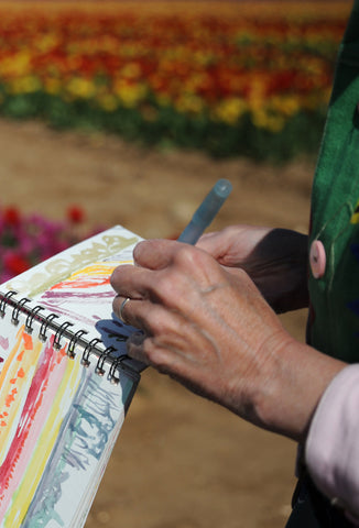 close up photo by Karen Harvey of Louise Stebbing Printmaker doing quick watercolour in tulip fields in Norfolk in aid of Tapping House Norfolk Hospice 
