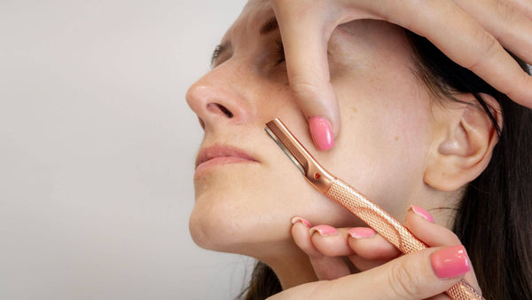 Woman holds her face to tight and prevent skin stretching whilst dermaplaning