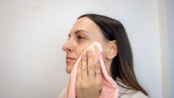 Woman dries her face with a towel