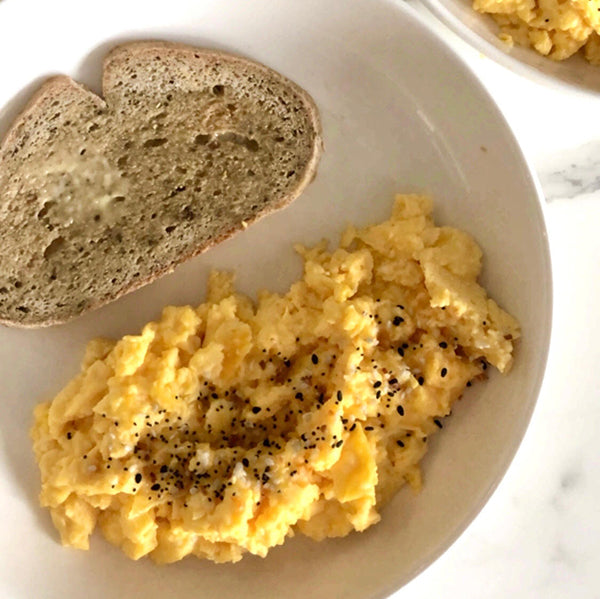 Scrambled eggs with a slice of Gluten Free Everyday Bread topped with raw butter