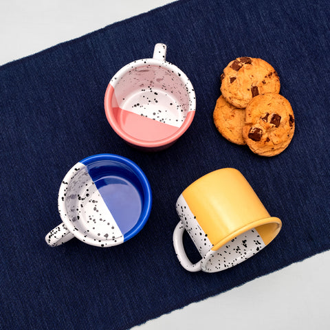 Three enamel mugs in blue, pink and yellow