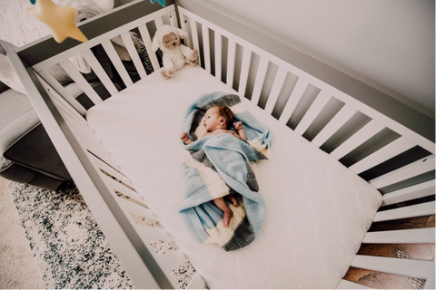 Newborn baby in a crib with a baby bath towel