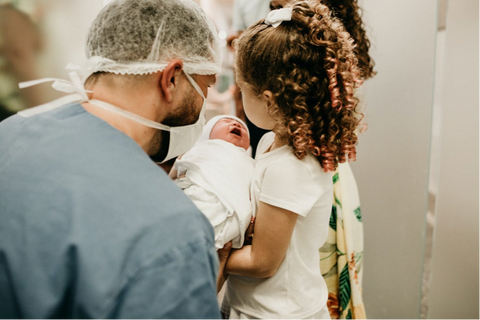 New father with big sister and newborn baby at birth