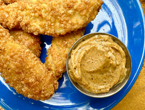 A blue plate of chicken tenders and a silver ramekin of spiced aioli made with Firecracker Dust from Well Seasoned Table.