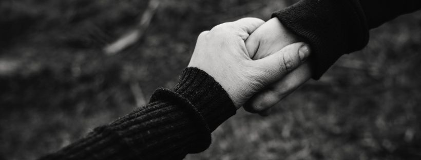 5 things you can do to support refugee communities - black and white image shows one person's hand supporting another persons hand