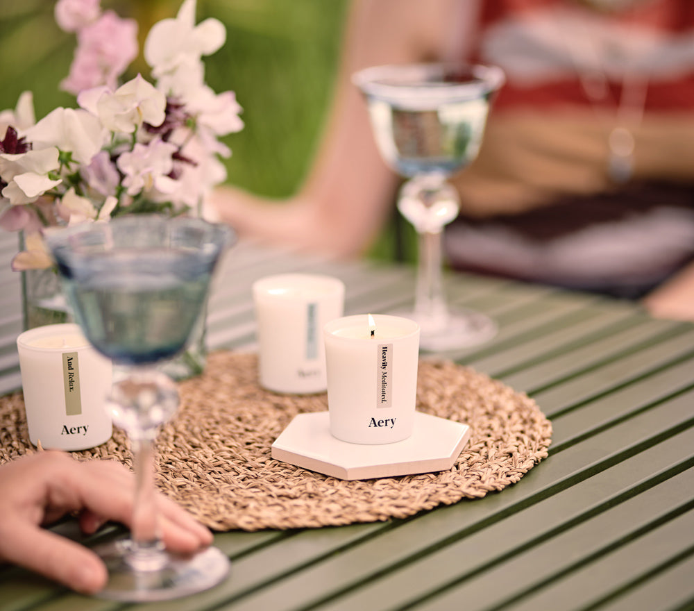 Two people drinking outside at a table with mini scented candles and flowers as table display