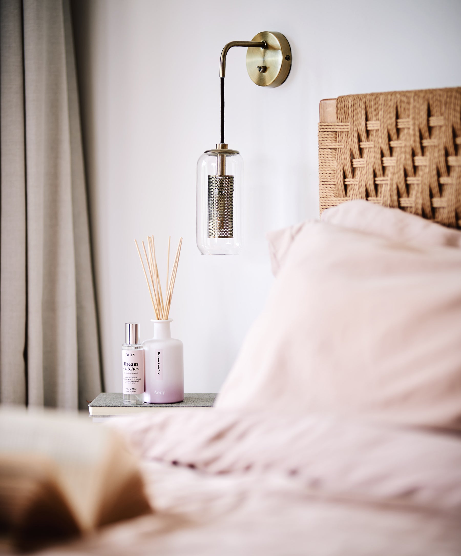 beside table setting, with open book and dusty pink bedding. Aery living reed diffuser and pillow mist displayed on table