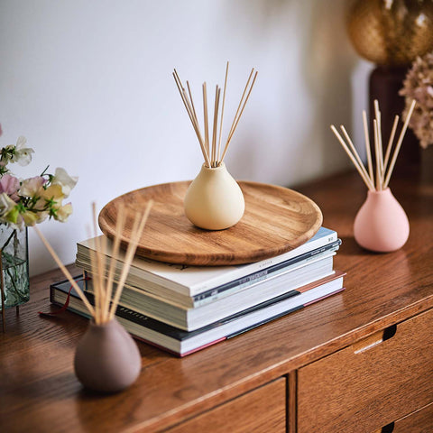 Fernweh diffusers displayed on wooden side board  with books and flowers