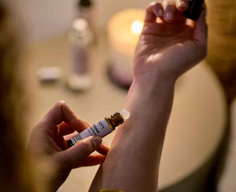 person using pulse point roller ball in bedroom setting