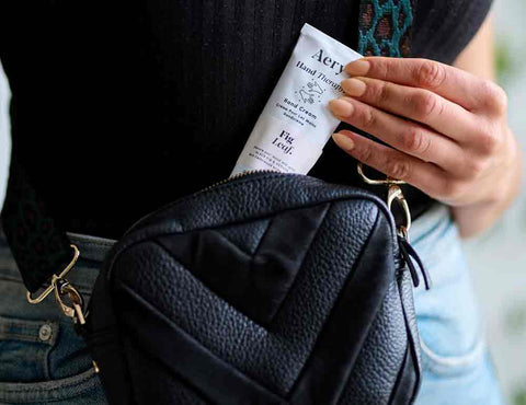 person pulling fig leaf hand cream out of hand bag