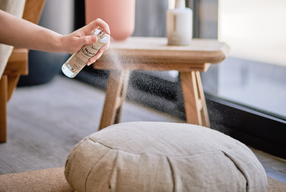 person spritzing yoga cushion with heavily meditated room mist