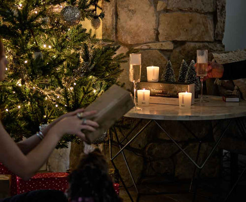 person handing gift to someone in front of the christmas tree