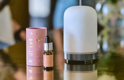 air diffuser on brass counter top with moroccan rose fragrance oil and packaging displayed next to it