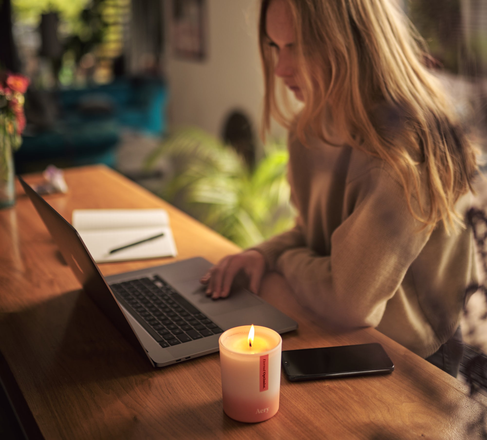 person working at home on a laptop next to a candle