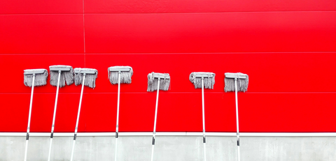 a lot of mops propped up again a bright red wall