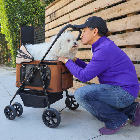 Dog dad giving kisses to white dog in brown pet stroller, 4-in-1 pet travel system