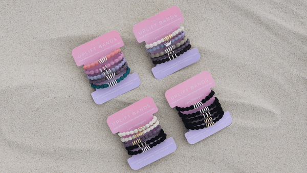 tyme uplift band hair ties palced on manifestation cards sit on a sandy beach