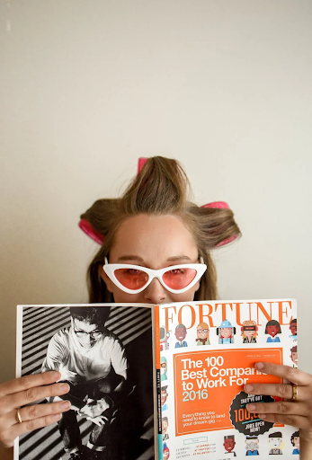 Image of a girl with blonde hair with rollers in holding a magazine.