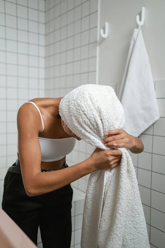 Woman drying her hair after washing it with anti-humidity shampoo.