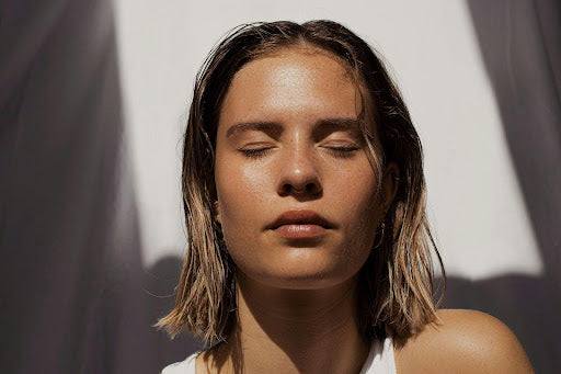 tanned-skin girl with short white hair laying out in the sun with her eyes closed.