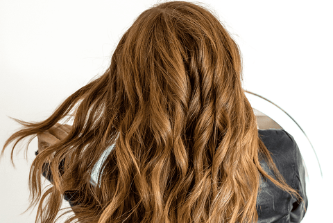 A woman brushing through her auburn-colored hair. 