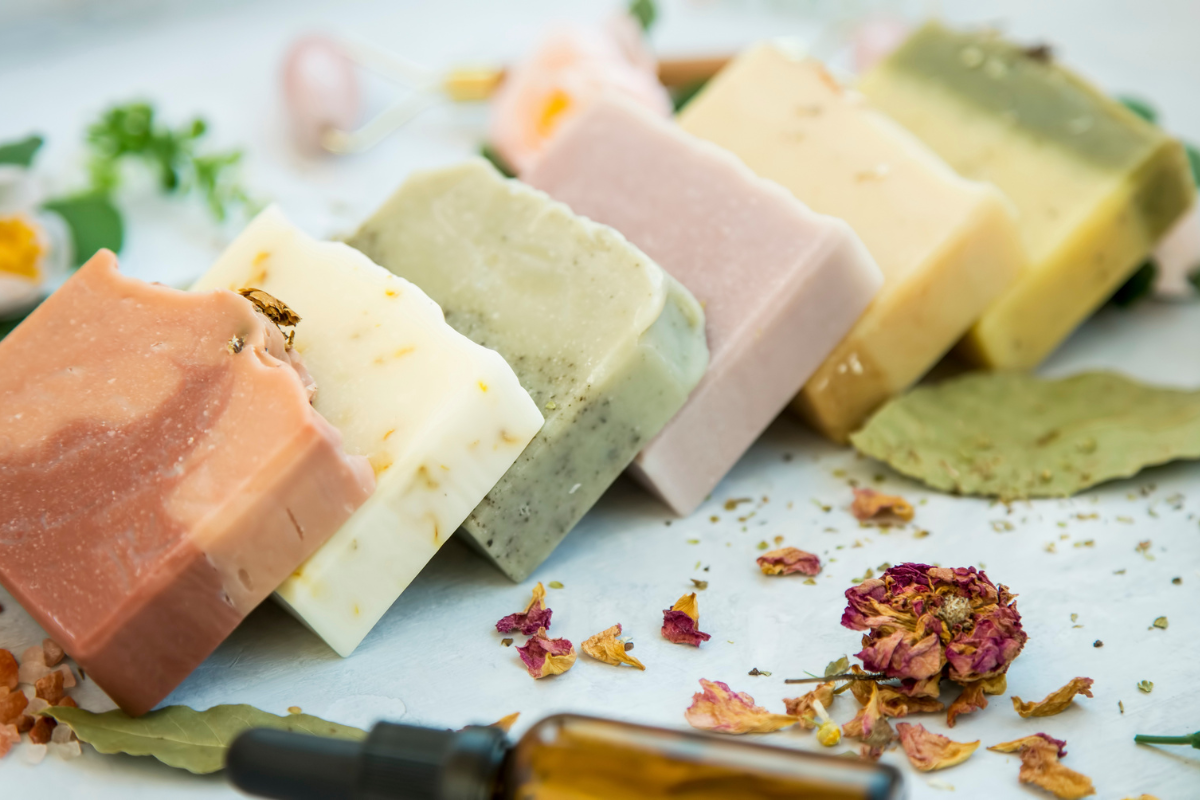 "A hand-made piece of natural soap: A mixture of fragrant essential oils and natural ingredients for gentle cleansing and care of the skin. 6 pieces in bright colors on a light background with dried flowers."