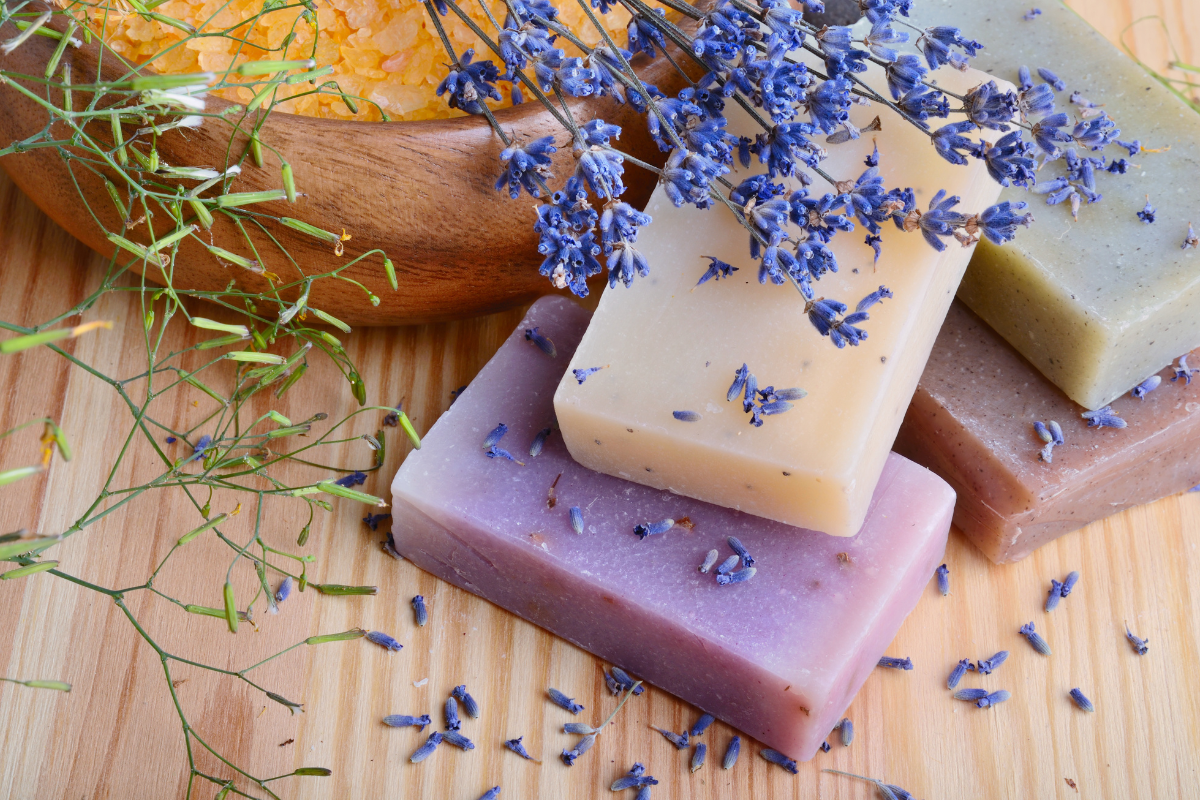 "A hand-made bar of natural soap: A blend of fragrant essential oils and natural ingredients for gentle cleansing and care of the skin. Purple with lavender on a wooden background."