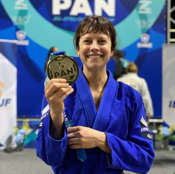 Atleta Kaycie Hall segurando medalha de ouro com kimono azul.