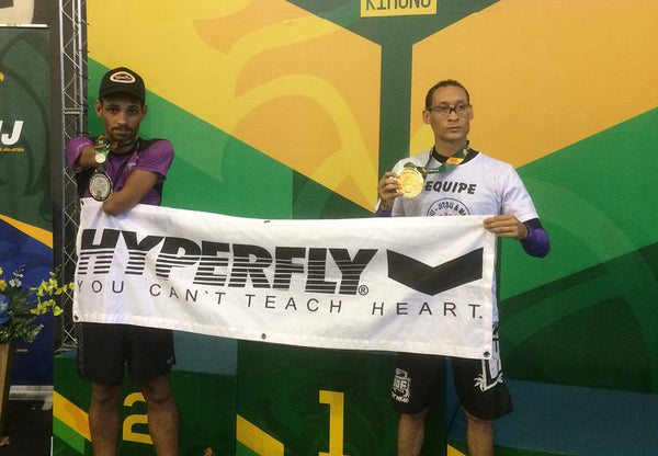 Luciano Mariano holding a Hyperfly banner with another competitor at a competition.