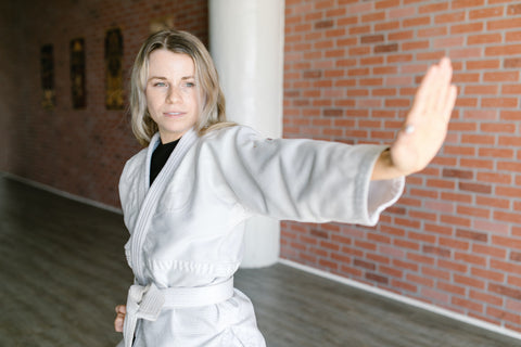 Woman practicing Jiu Jitsu in a white kimono.