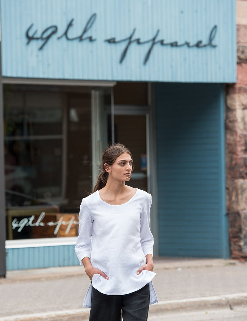 model in front of 49th Apparel storefront wearing white linen Jenn Tunic and black linen Mara Pants. 