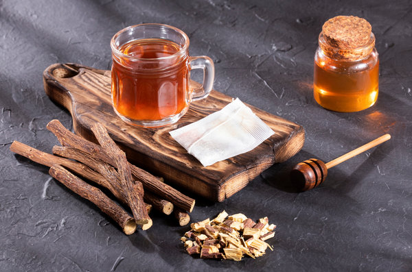 A cup of licorice tea on a wooden cutting board. 