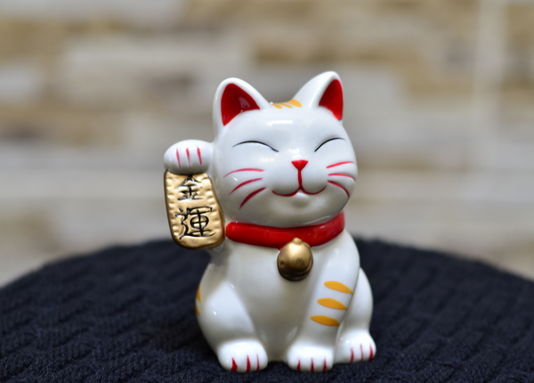 White lucky cat with a red collar that has a gold bell. 