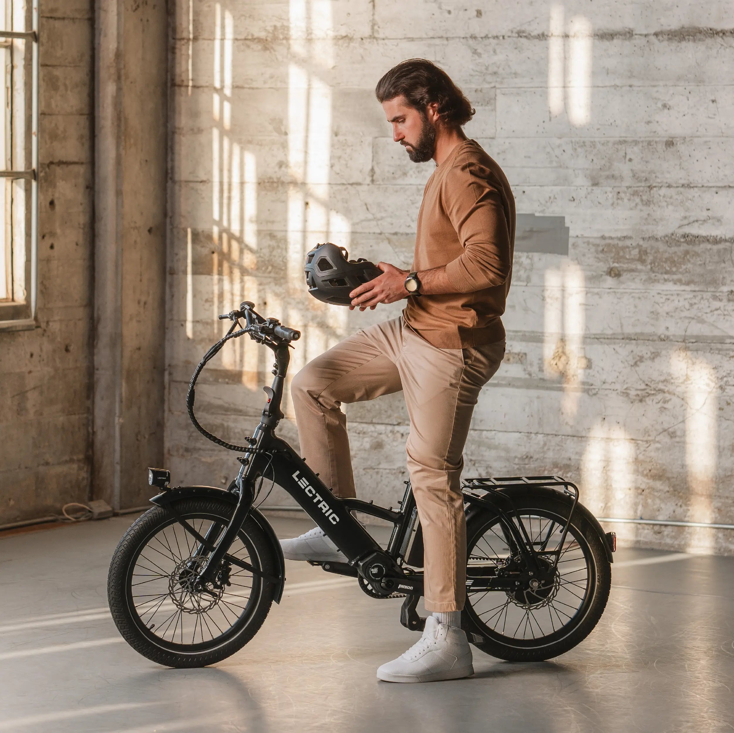 man putting on helmet sitting on Lectric ONE eBike in industrial building
