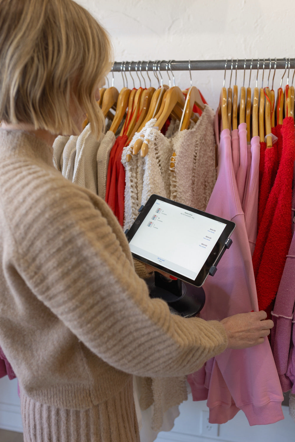 Una mujer en una tienda usando el sistema Shopify POS mientras mira ropa