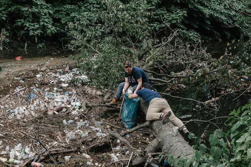 Bryan y Mike de United By Blue recogiendo basura de un río