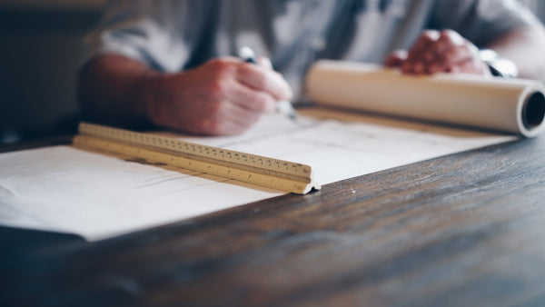 Hombre diseñando en un plano sobre una mesa