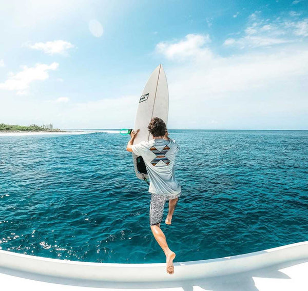 Guy jumping off a bote with a surfboard