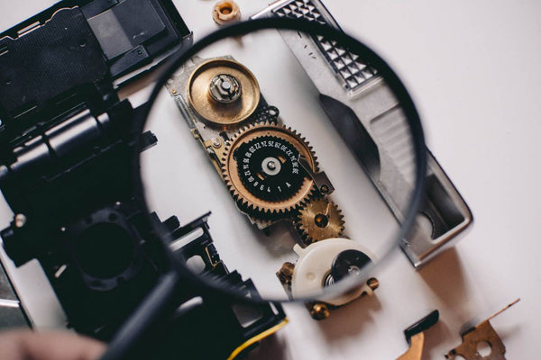 Photo by Shane Aldendorff-person using magnifying glass to see gold and white device gear