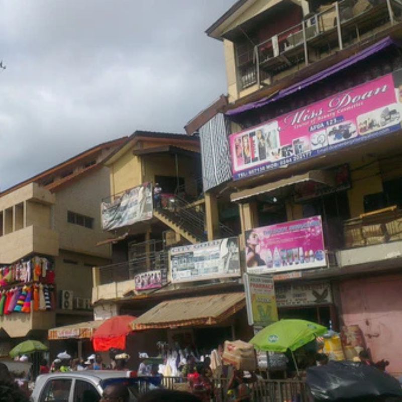 Street view of Accra’s vibrant market district, filled with local shops, market stalls, and colorful umbrellas.