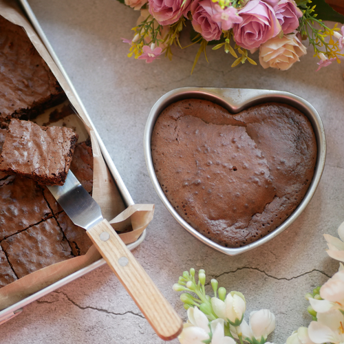 Brownie Heart in a tin with a tray of brownies and roses in the background