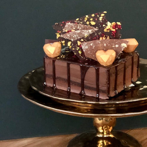 A Dello Mano Brownie Jewel Box Cake on a gold stand presentation