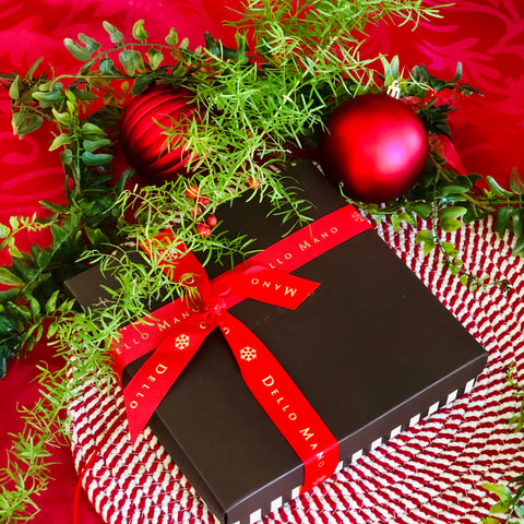 A Dello Mano Brownie Gift Box with red Christmas ribbon, pine and red baubles