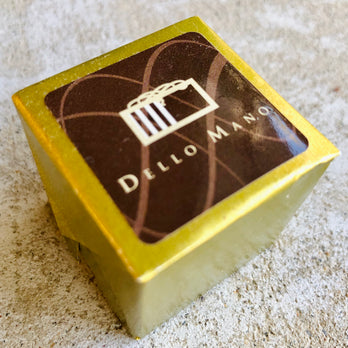 A Dello Mano Luxury Brownie Cube wrapped in iconic gold foil