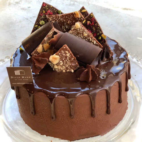 A chocolate mousse cake with decorations and a label that says Dello Mano