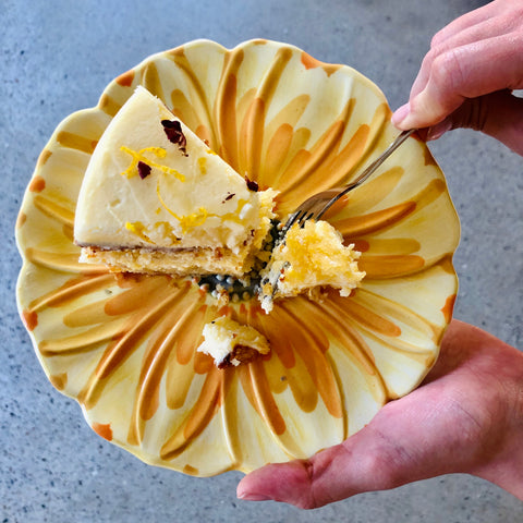 A slice of Orange Almond Gluten Free cake on a yellow plate with hand cutting with fork