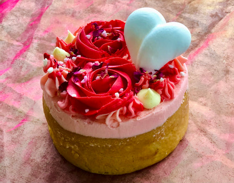 a pink cake with red valentines day roses made from buttercream frosting