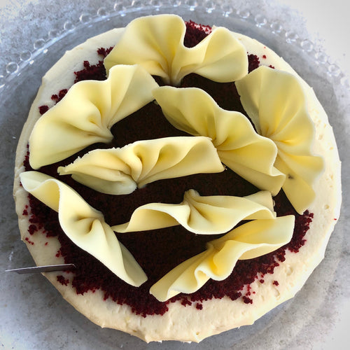 Looking down on the top of Red Velvet cake with cream cheese frosting and white chocolate fan decoration