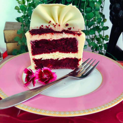 An open slice that shows red velvet cake and cream cheese with afork