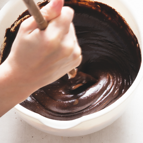 A hand mixing brownie batter
